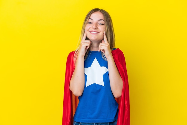 Super Hero Romanian woman isolated on yellow background smiling with a happy and pleasant expression