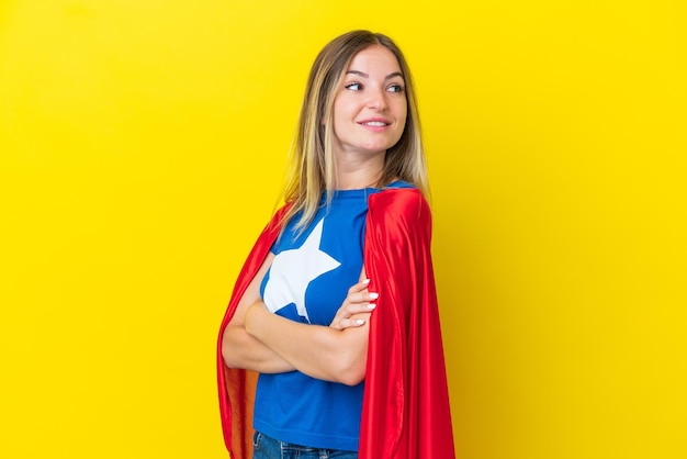 Super hero romanian woman isolated on yellow background with\
arms crossed and happy