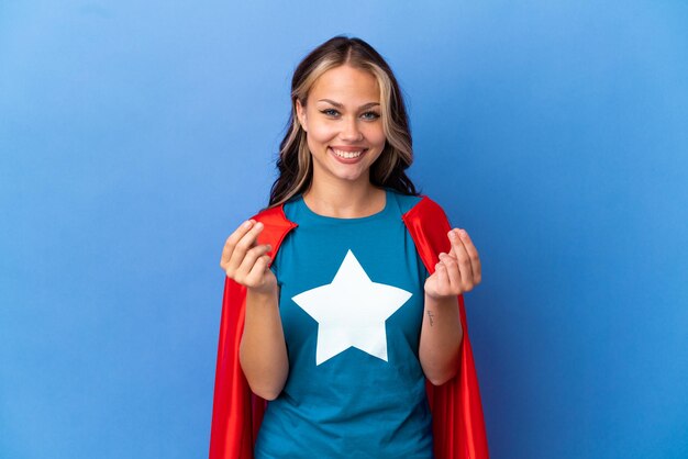 Foto super hero ragazza adolescente isolata su sfondo blu che fa gesto di denaro