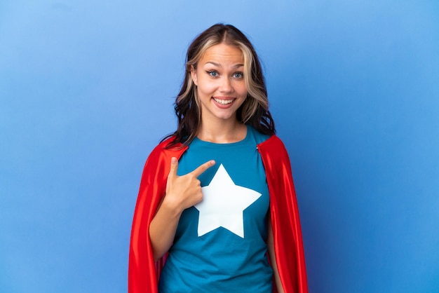 Super Hero Teenager girl isolated on blue background with surprise facial expression