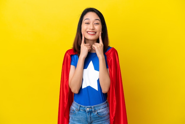 Super hero vietnamese woman isolated on yellow background smiling with a happy and pleasant expression