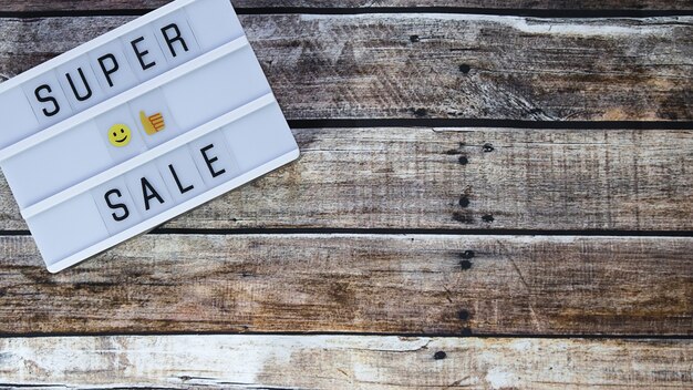 Photo super sale word written on lightbox on brown wooden. flat lay, top view.