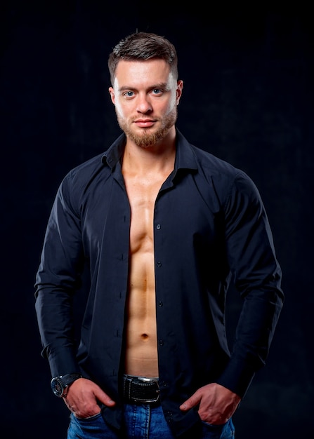 Super sexy man with tan abs and chest. Athletic man with unbuttoned dark shirt on gray background. Studio portrait