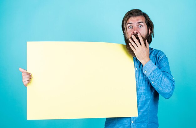 Foto super verkoop leeg papier voor uw informatie kapper concept verrast hipster met baard op papier vel lege plek voor kopieerruimte hulp nodig bebaarde man met paaien gezocht