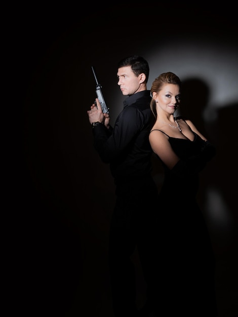 Superagenten een prachtige blondine in een zwarte avondoutfit en een man met een pistool achter haar rug een luxe...