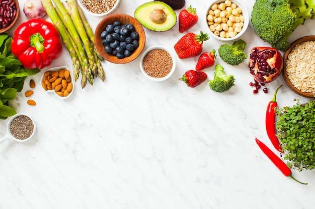 Фото Суперпродукты на сером фоне с копией пространства. фрукты и овощи, семена и орехи. здоровая веганская еда.