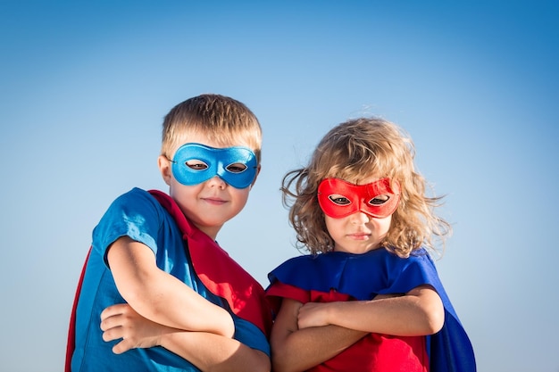 Superheld kinderen tegen zomer hemelachtergrond Kinderen plezier buitenshuis Jongen en meisje spelen Succes en winnaar concept