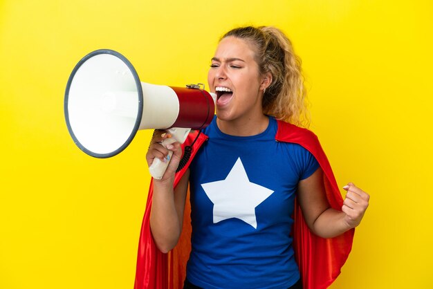 Superheldenvrouw geïsoleerd op gele achtergrond die door een megafoon schreeuwt om iets in zijpositie aan te kondigen