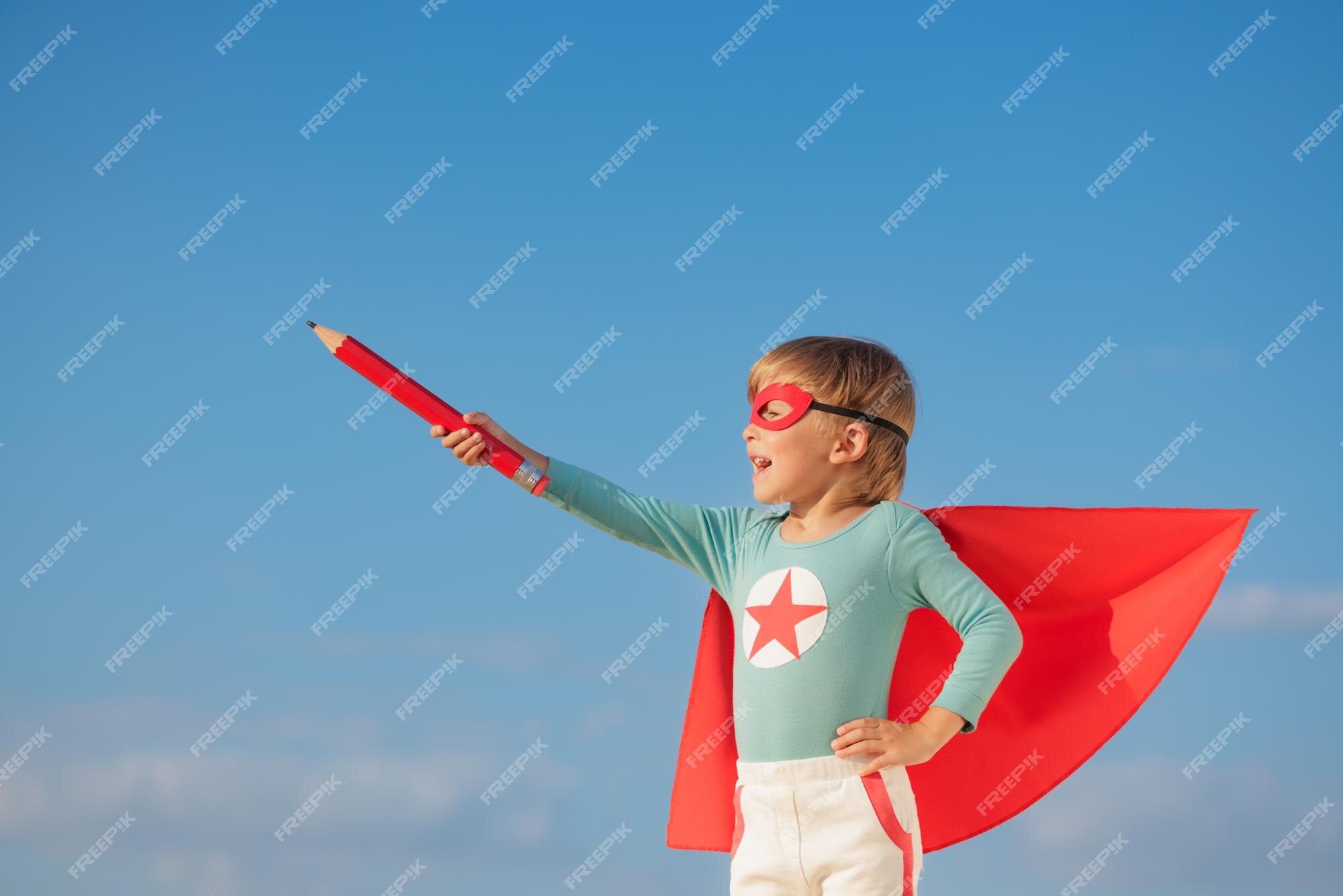 Power. Child pretending to be a superhero with his friends sitting around  him. Kids excited, inspired by their strong friend in red coat isolated on  white background. Dreams, emotions concept Stock Photo 