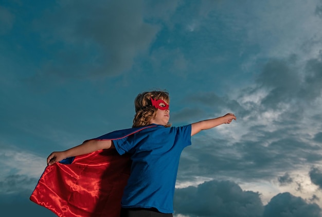 Superhero kid against blue sky background copy space
