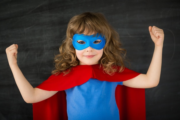 Superhero kid against school blackboard