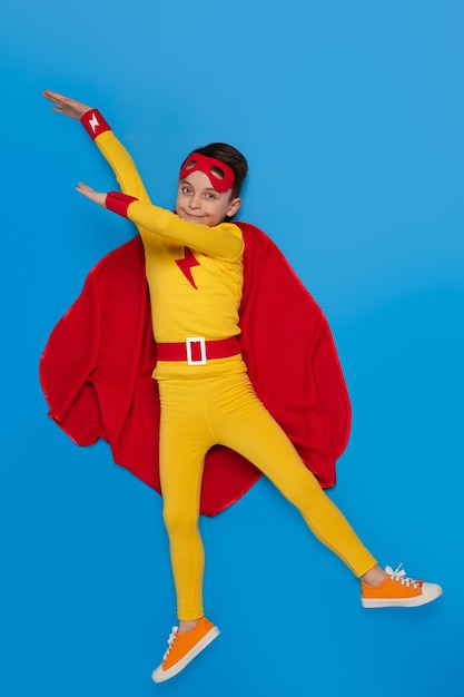 Photo superhero kid in costume pointing away in studio