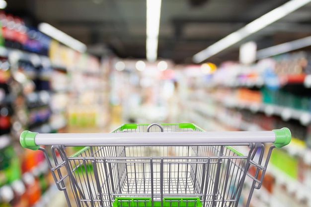 Supermarket aisle with empty shopping cart at grocery store retail business concept