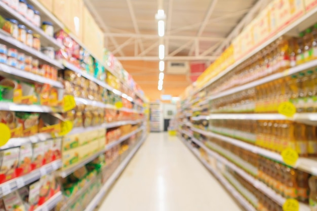 Il corridoio del supermercato con gli scaffali dell'olio vegetale per condire e cucinare sfoca lo sfondo interno