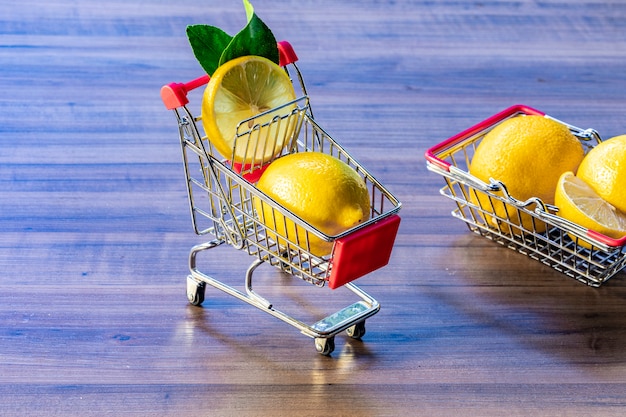 녹색 잎과 레몬을 운반하는 슈퍼마켓 바구니와 슈퍼마켓 카트