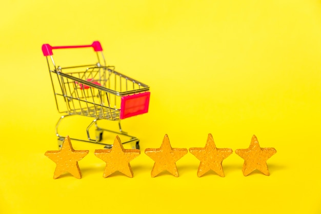 Supermarket grocery push cart for shopping and gold stars rating isolated on yellow background