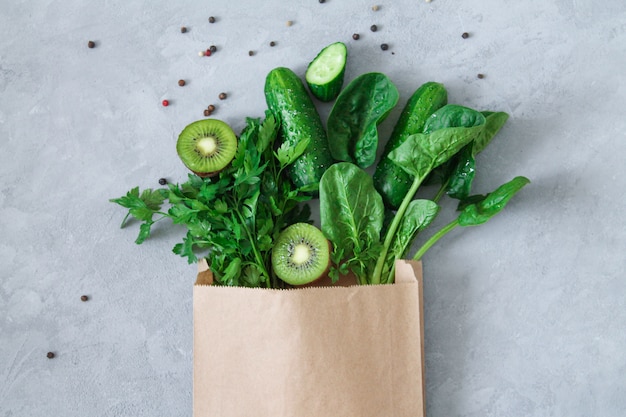 Supermarket paper grocery bag with green clean food on light gray stone table top view