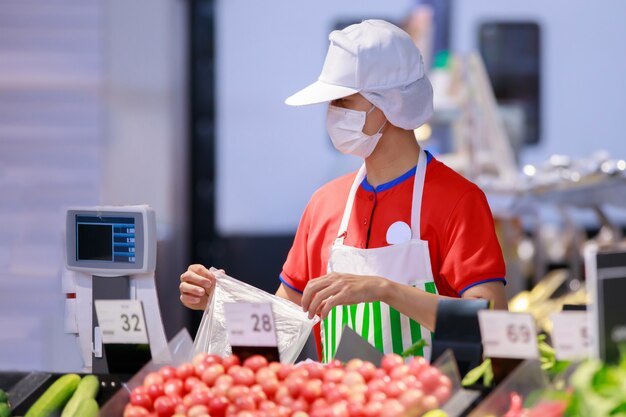 Supermarket staff in medical protective mask working at supermarket