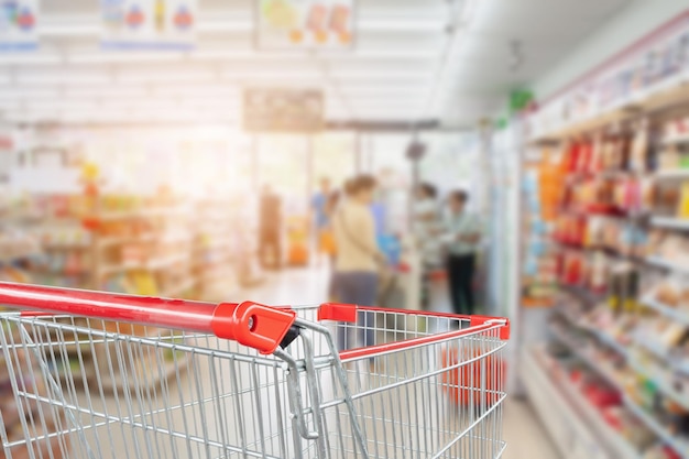 Supermarkt gangpad vervagen abstracte achtergrond met lege rode winkelwagen