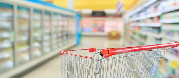 Supermarkt koelkasten vriezer gangpad vervagen intreepupil achtergrond met lege rode winkelwagen