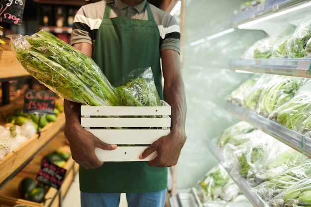 Supermarktarbeider die Doos Groenen draagt