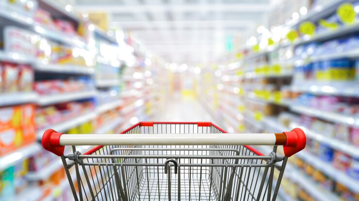 Foto supermarktdoorgang met leeg rood boodschappenwagentje.