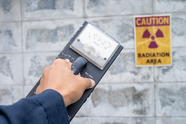 Supervisor gebruikt de meetmeter om het stralingsniveau in de radioactieve zone te controleren