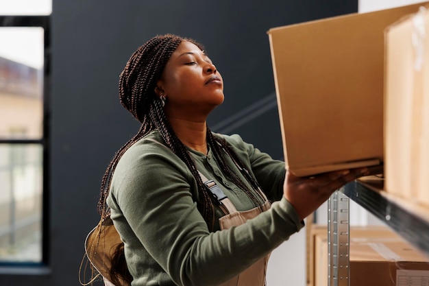 Supervisor putting cardboard boxes on metallic shelves, preparing customers online order in storehouse. Storage room employee working at merchandise inventory doing products quality control