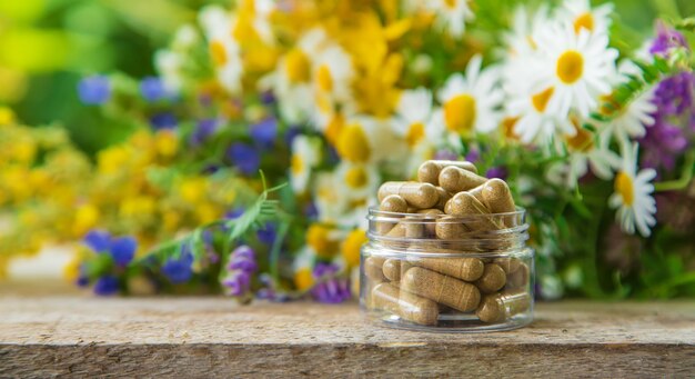 supplementen en vitamines met geneeskrachtige kruiden op een houten tafel met een wazige vegetatieachtergrond