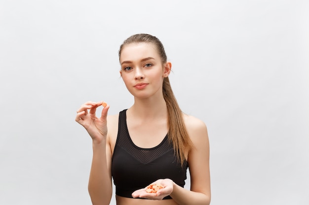 Supplements, Sports, Vitamins, Diet, Nutrition, Healthy Eating, Lifestyle. Close up of smiling fitness woman taking pill with cod liver oil Omega-3 , vitamin D, E, A fish oil capsules.