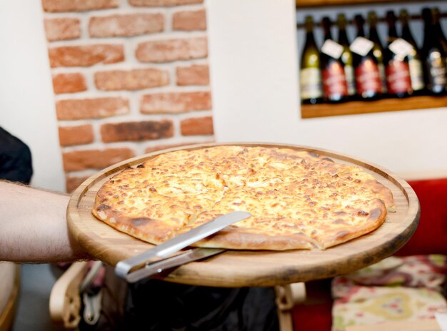 Foto la fornitura di pizza al formaggio in un ristorante come cameriere da vicino