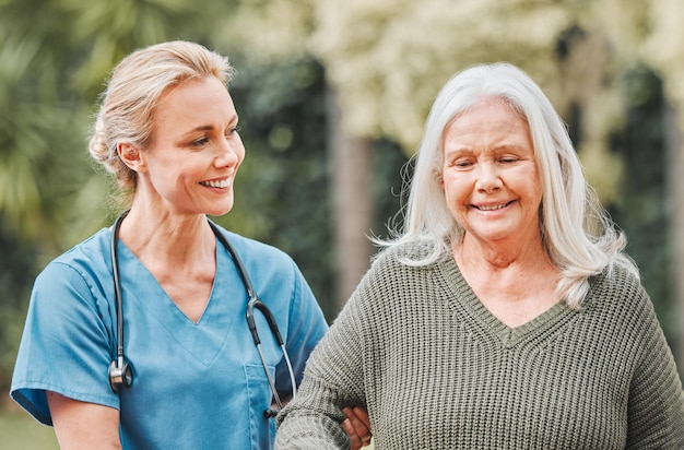 Photo support smile and nurse walking elderly woman in a garden to relax wellness and morning exercise in the lawn trust nursing home and caregiver help senior person smile and happy for outdoor walk