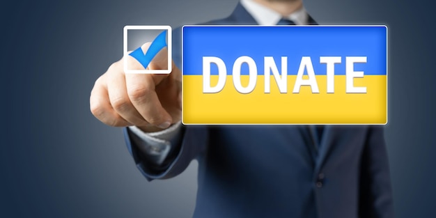 Photo support of ukraine concept official person or politician man in the suit pushes donate button on ukrainian flag