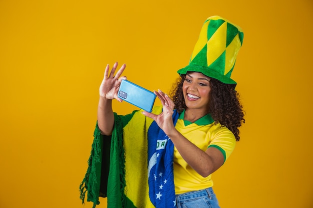 Supporter of the brazilian football team celebrating a goal by\
watching the smartphone