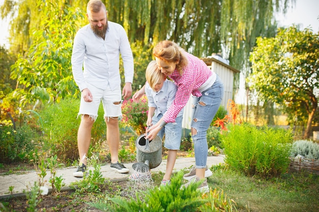 Supporting hands. Happy family during watering plants in a garden outdoors. Love, family, lifestyle, harvest, autumn concept. Cheerful, healthy and lovely. Organic food, agriculture, gardening.