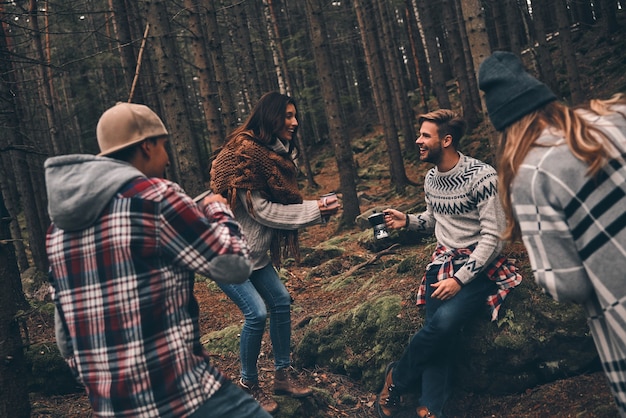 協力的な友達。森の中でハイキングしながら一緒に時間を過ごす幸せな若者のグループ