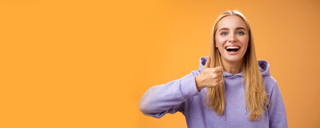 Supportive happy glad young blond attractive woman in hoodie adore perfect good idea show thumbs up person