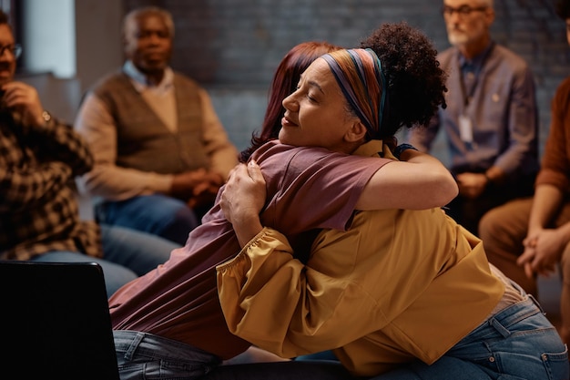 Supportive women embracing during group therapy at mental health center