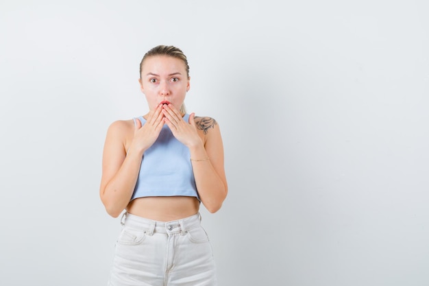 Suprised girl is closing her mouth with her hands on white background