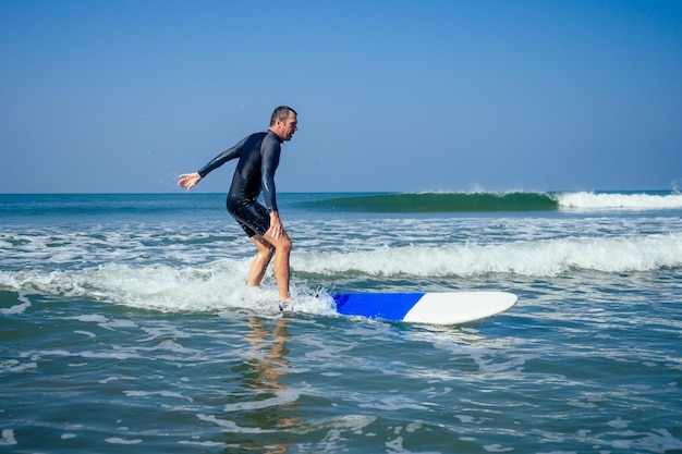 Istruttore di surf che mostra come cavalcare sulle grandi onde a goa in india