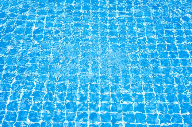 Surface of blue water in swimming pool with sun reflection. Ripple wave in pool. 
