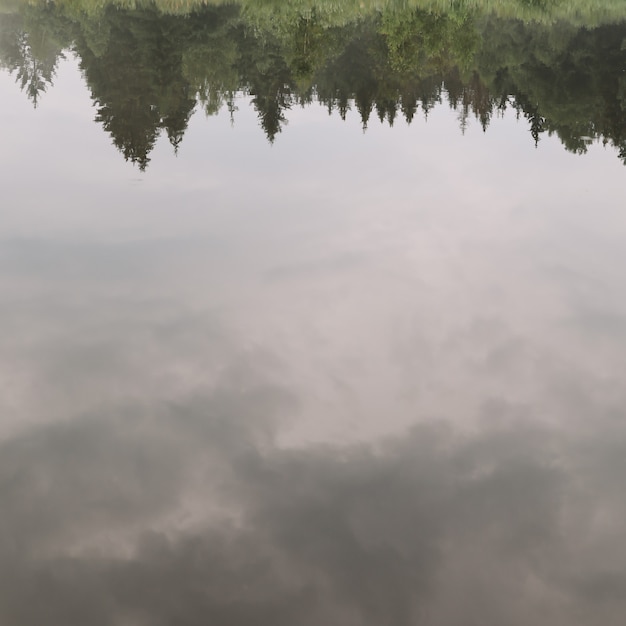 Surface of calm water with reflection of cloudy sky