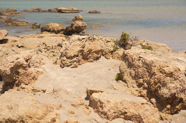 Surface of clear water on tropical sandy beach with stones in Crete Greece.