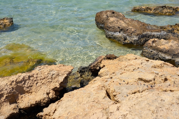 Superficie di acqua limpida sulla spiaggia sabbiosa tropicale con pietre in creta grecia.