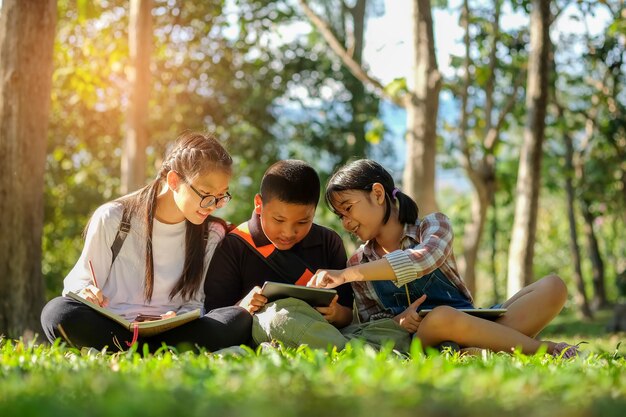 Photo surface level of children discussing over digital tablet in park