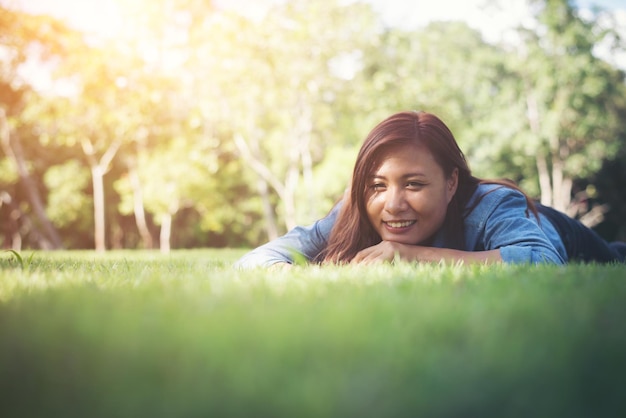 写真 公園の草の上に横たわっている幸せな女性の表面レベル