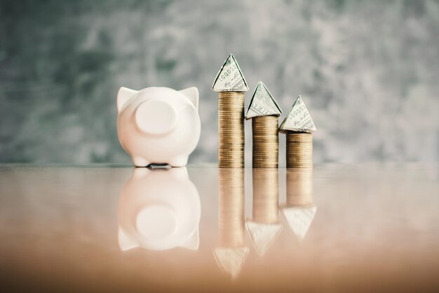 Photo surface level of piggy bank and coins stack with currency pyramid