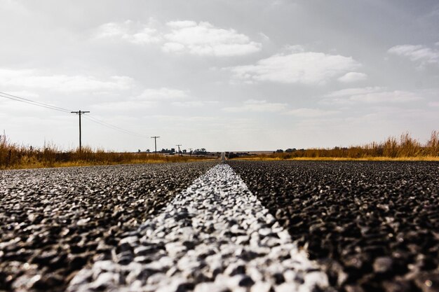 Surface level of road amidst field against sky