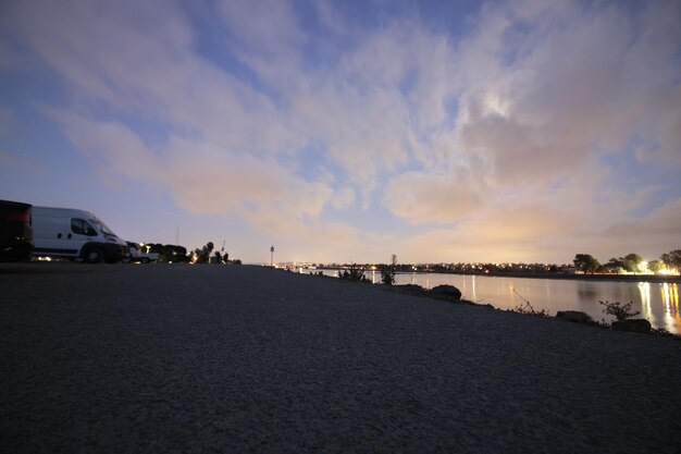 Surface level of street by sea against sky during sunset