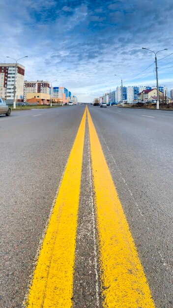 Surface level of yellow road against sky in city